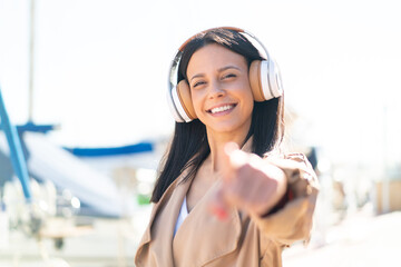 Poster - Young woman at outdoors listening music and pointing to the front