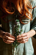 © Caterina Trimarchi - Redhead Woman holding in her hands a bunch of blooming rosemary. Herbalist woman preparing fresh scented organic herbs for natural herbal methods of treatment. Alternative medicine.