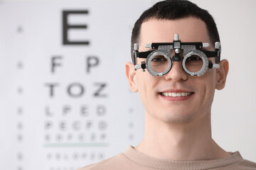 Poster - Young man with trial frame against vision test chart