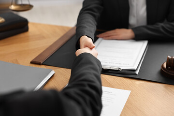 Poster - Notary shaking hands with client at wooden table in office, closeup