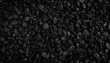 © LADALIDI - Close-up of textured black rocks or gravel, uniformly spread. Highlights natural patterns and shapes