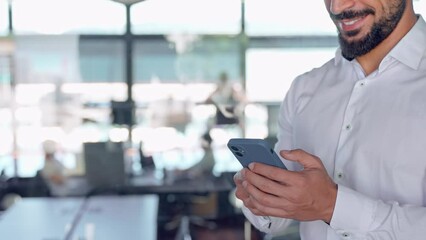 Wall Mural - Young business man, businessman employee standing in office holding smartphone in hands using apps on cell phone doing bank payments on cellphone at work. Mobile technology. Close up view. Copy space