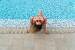 Chica joven rubia disfrutando de sus vacaciones en la piscina del hotel