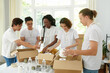© DragonImages - Group of students volunteering in charity organization, packing boxes for homeless people