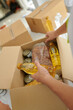 © DragonImages - Charity organization volunteer packing canned food, nuts and vegetable oil in box for people in need