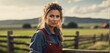 portrait of a young female farmer wearing overalls standing and leaning on wooden fence outdoor on rural area with copy space