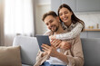 © Prostock-studio - Happy woman embracing husband while using tablet on sofa