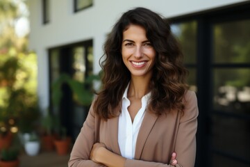 Wall Mural - An attractive young woman with long brown hair wearing a suit jacket smiles confidently at the camera