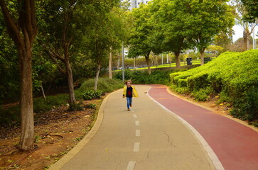 A child runs along the road. Empty asphalt road. boy running boy is walking in the park. Portrait of a cute child.