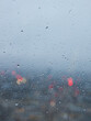 A close up photograph of raindrops on a window, looking out over an urban cityscape at dusk. Evening on a grey and cloudy day. 