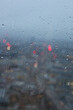 A close up photograph of raindrops on a window, looking out over an urban cityscape at dusk. Evening on a grey and cloudy day. 