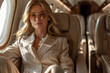 Elegant lady in a private jet. Businesswoman or rich woman  in airplane business class, wearing beautiful clothes.