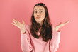 Portrait of clueless questioned girl raise arms palms shrug shoulders not know isolated on pink color background.