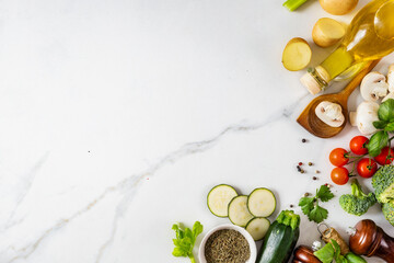 Wall Mural - Healthy food cooking ingredients background with fresh vegetables, herbs, spices and olive oil on marble table with copy space top view