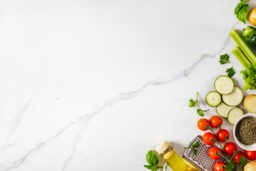 Wall Mural - Healthy food cooking ingredients background with fresh vegetables, herbs, spices and olive oil on marble table with copy space top view