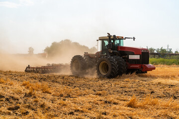 Wall Mural - A tractor with a plow plows the field after harvesting.