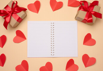 Wall Mural - Open notebook with empty white sheets, red hearts and gift boxes on a beige background