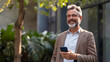 © Annemarie - Active mature senior business man executive using mobile cell phone outside on a sunny day. Retired man using financial app on smartphone. Communication concept.