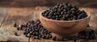 A rustic wooden bowl filled to the brim with aromatic black peppercorns