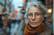 © familymedia - A fashionable lady exudes confidence and elegance on a bustling street, her smile framed by stylish glasses and a chic scarf