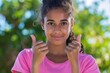 © LimeSky - Portrait of a young woman with pink shirt and thumbs up signs isolated outdoors Positive emotions and body language