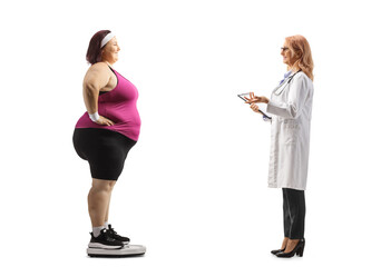 Canvas Print - Female doctor talking to a corpulent woman in sportswear on a weight scale