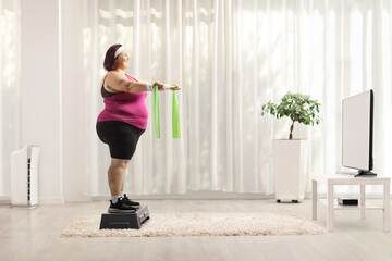 Wall Mural - Full length profile shot of a plus size woman exercising with elastic band