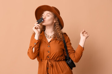 Canvas Print - Beautiful young woman with credit card on brown background