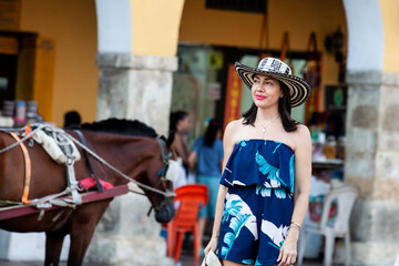 Wall Mural - Beautiful woman wearing the traditional Colombian hat called Sombrero Vueltiao at the Carriage Square on the historical streets of Cartagena de Indias walled city