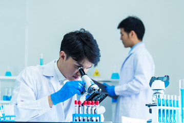 scientist man look into microscope research in science laboratory. asian scientist looking equipment