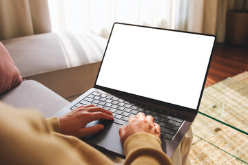 Mockup image of a woman working and typing on laptop computer with blank screen while sitting on sofa at home