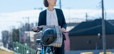 Fototapeta  - 屋外で自転車をおすスーツを着た女性