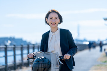 屋外で自転車をおすスーツを着た女性