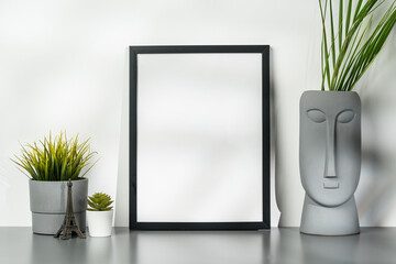 Wall Mural - Black wooden frame and gray vase with plant leaves against white wall