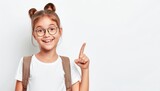 Fototapeta Storczyk - Young Girl With Glasses and Backpack Pointing Upwards in Front of a White Background