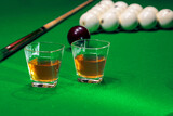 Fototapeta Sypialnia - Glass of whiskey on billiard table with cue and billiard balls in background