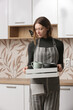 © triocean - Housewife in apron tidying up crockeries in the kitchen, domestic life, general organization and decluttering concept