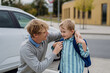 © Halfpoint - Father saying goodbyeto to son in front of school building, hugging him and helping with backpack. Dad heading to work. Concept of work-life balance for parents.