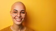 Smiling bald woman with glasses against yellow background.