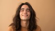 © Z A C - Young man with long hair and glasses smiling against a beige background.