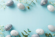 canvas print picture - Festive Easter composition: Directly top view of beautiful grey eggs, gypsophila blooms, and eucalyptus branches arrayed on a pale blue ground, with a vacant spot for textual content or advertising