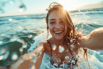 Wall Mural - young woman splashes water and takes a selfie in the sea with blue sea sunset