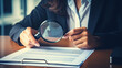 woman reading a contract paper with magnifying glass. audit concept