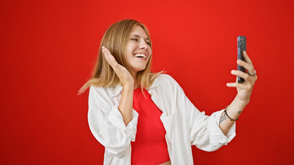 Sticker - Blonde woman in white smiling joyfully while taking a selfie against a red background