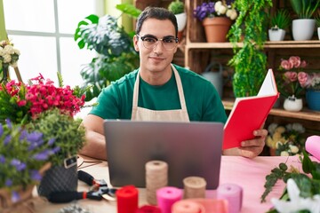 Sticker - Young hispanic man florist using laptop reading book at flower shop