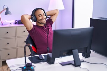 Poster - Young latin man streamer smiling confident relaxed with hands on head at gaming room