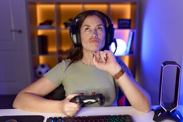 Sticker - Beautiful brunette woman playing video games wearing headphones thinking concentrated about doubt with finger on chin and looking up wondering