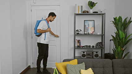 Poster - Hispanic man with beard checks door before leaving modern apartment with decor and plants.