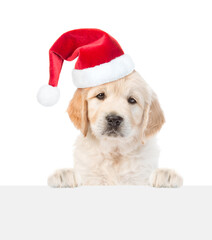 Wall Mural - Cute Golden retriever puppy wearing santa hat looks above empty white banner. isolated on white background