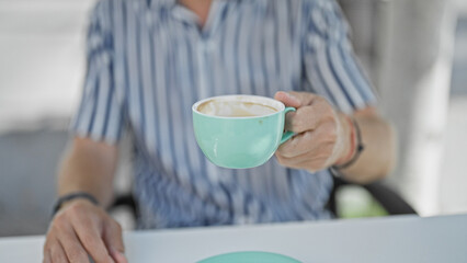 Sticker - A young man enjoys a cappuccino on a cafÃ© terrace in the city, embodying urban relaxation and style.